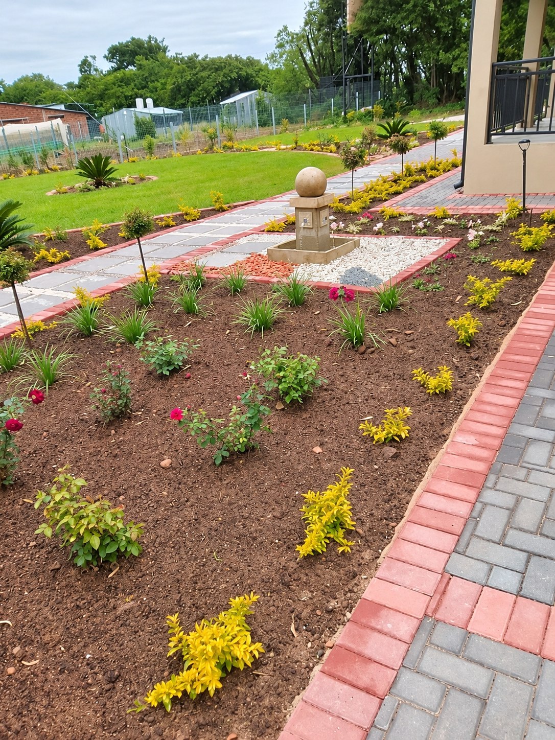 Newly planted flower beds beside garden paving